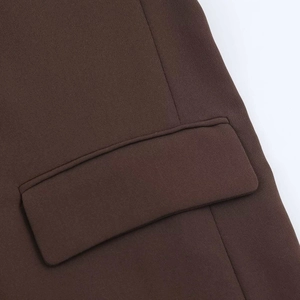 Detailed macro view of the brown blazer's flap pocket with precise stitching