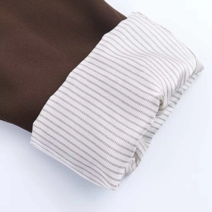Detail of dark brown blazer cuff showing smooth wool fabric and blue striped inner lining