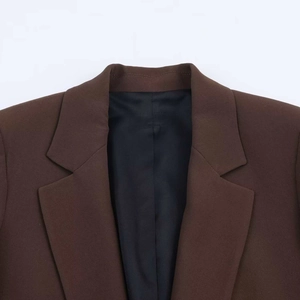 Detail of notched lapel on a coffee brown three-quarter sleeve blazer with twill texture