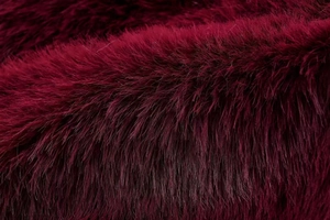 Macro view of luxurious deep burgundy faux fur vest fabric showing dense silky texture