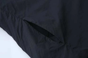 Close-up of side pocket stitching and ripstop fabric texture on black winter coat