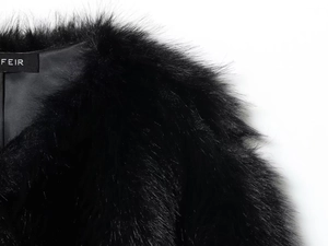 Detail of a plush black faux fur collar with brand label on a soft textured jacket