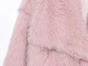 Détail d'un manteau en fausse fourrure rose montrant la texture et la doublure satin