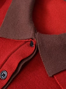 Detail of red and brown knitted polo sweater featuring black buttons and collar texture