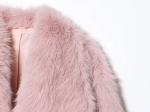 Détail de manteau en fausse fourrure rose montrant les fibres douces et la doublure satin