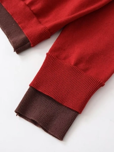 Close-up of red knit sweater featuring brown ribbed cuffs and high-quality fabric texture