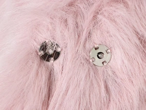 Détail des boucles magnétiques argentées sur une veste chic en fausse fourrure rose