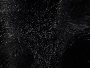 Detail shot of black faux fur texture with a woven rope knot loop fastener