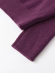 Close-up of deep purple knit sweater featuring ribbed cuffs and wool texture detail