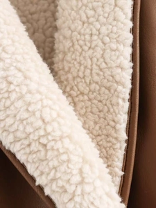 Detail of winter jacket showing brown faux leather exterior and white faux fur lining