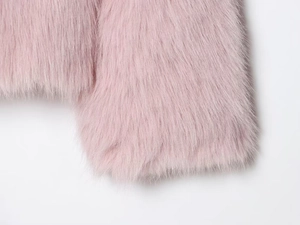 Détail de la texture douce en fausse fourrure rose sur la manche de la veste