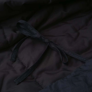 Detail of black quilted fabric with a tied drawstring on a long-sleeve kimono jacket