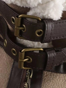 Detail of winter jacket with brown faux leather straps, metal buckles and white fleece lining