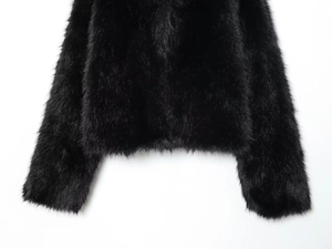 Close-up of the plush faux fur hem and sleeves on a glossy black fashion coat