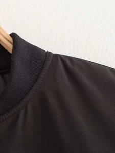 Detail of black bomber jacket with ribbed collar and high-quality synthetic fabric texture