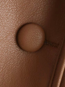 Close-up of brown faux leather texture with stitching and a matching wrapped button