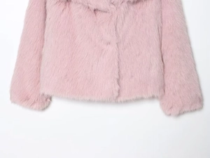 Détail montrant la texture moelleuse et les fibres douces de la veste en fausse fourrure rose