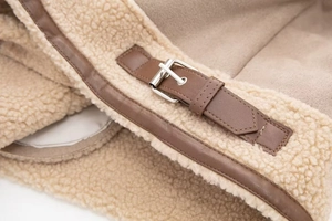 Detail of faux shearling jacket featuring brown leather straps and silver metal buckles