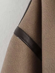 Macro detail of khaki suede jacket with contrast faux leather trim and neat stitching