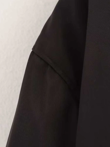 Detailed view of the shoulder seam and twill fabric texture on a black oversized jacket