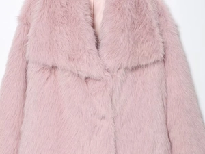 Détail d'un manteau en fausse fourrure rose montrant le col à revers et la doublure