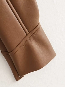 Close-up of brown leather sleeve cuff showing detailed texture and precision stitching