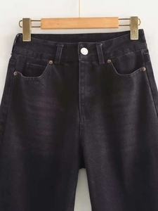 Detail shot of high-waisted black washed denim jeans with classic pocket and metal button
