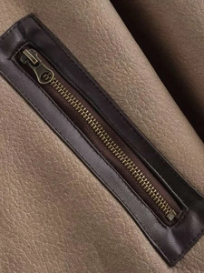 Close-up of brown faux shearling jacket with metal zipper and dark leather trim detailing