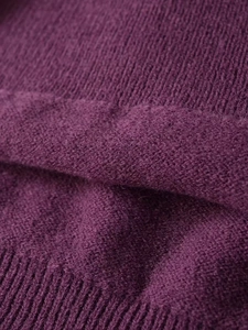 Detailed close-up of dark purple knit sweater fabric showing smooth texture and ribbed hem