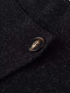 Detail of dark grey knit fabric showing fine texture and brown marble-pattern button