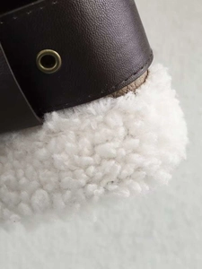 Detail of dark brown faux leather jacket with warm white faux shearling lining