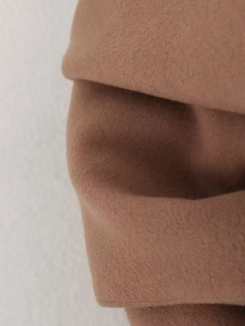 Macro shot of soft camel wool fabric texture on a long winter coat for women