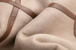 Macro shot of khaki faux suede fabric texture and dark brown leather piping detail
