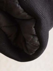 Detail of ribbed knit cuffs and quilted lining on a black silhouette bomber jacket