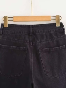 Detail view of high-waisted dark grey denim jeans with back pockets on a wooden hanger