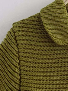 Dettaglio ravvicinato della maglia verde erba con colletto e spalla in vista
