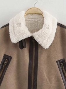 Detail of a brown faux suede jacket with white faux shearling lining and metal zippers