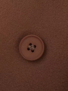 Detailed macro view of dark brown wool coat fabric with a matching four-hole button