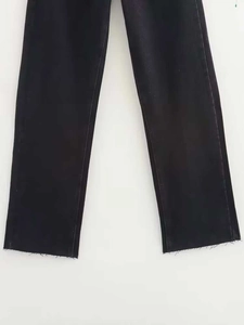 Detail shot of black straight leg denim jeans featuring a trendy raw hem finish