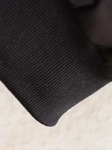 Detail of ribbed knit cuffs and hem on a black oversized baseball jacket