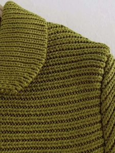 Dettaglio del maglione in maglia verde oliva con trama a costine e scollo