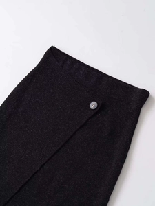 Close-up of asymmetrical waist detail on dark gray knit skirt with round button finish