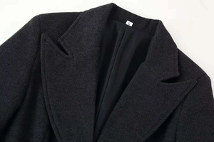 Dettaglio del risvolto del cappotto di lana grigio scuro con etichetta taglia S e fodera