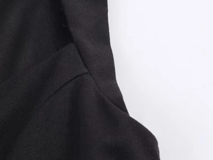 Detailed close-up of the black woven fabric texture and premium stitching on the romper