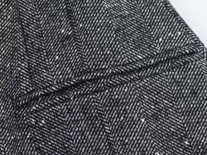 Macro shot of black and white herringbone wool fabric texture on a short blazer coat