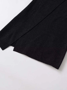 Detail shot of a dark grey knitted skirt featuring a clean slit and premium ribbed fabric