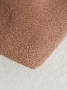 Macro detail of the soft camel wool fabric texture on this long winter coat scarf collar