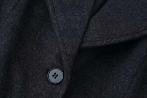 Dettaglio cappotto in lana grigio scuro con bavero classico e bottone nero di alta qualità