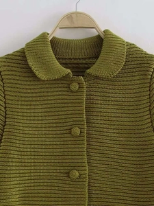 Dettaglio del cardigan in maglia verde oliva con colletto a rever e bottoni monopetto