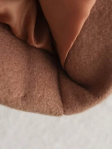 Macro detail of brown wool coat fabric featuring smooth silk-like lining and fine texture